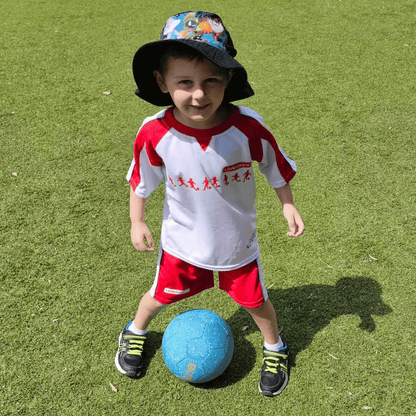 Happy, little boy standing on grass with blue glitter soccer ball between his feet.