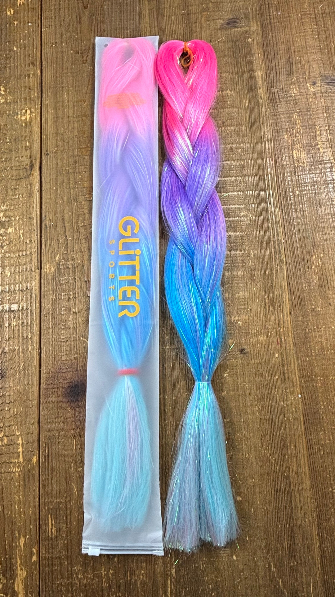 Ombre hair extension tinsel braids graduating from bright pink through purple, aqua and light blue on wood background