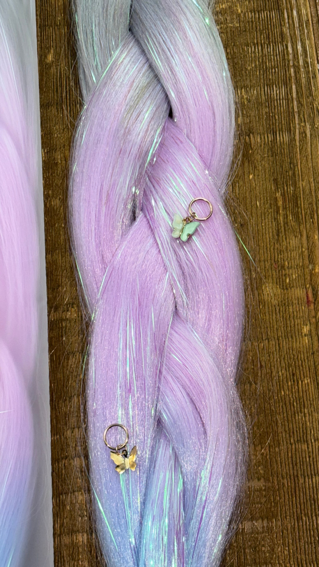 Close up of purple, silver and blue ombre tinsel braid with gold butterfly hair charms on wood background.