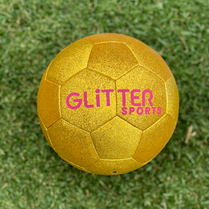 Gold glitter kids soccer ball with pink 'Glitter Sports' logo on grassy background.