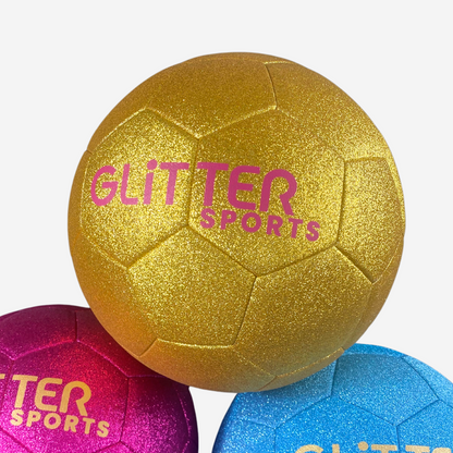 Gold glitter kids soccer ball with pink 'Glitter Sports' logo sitting on top of pink and blue soccer balls.