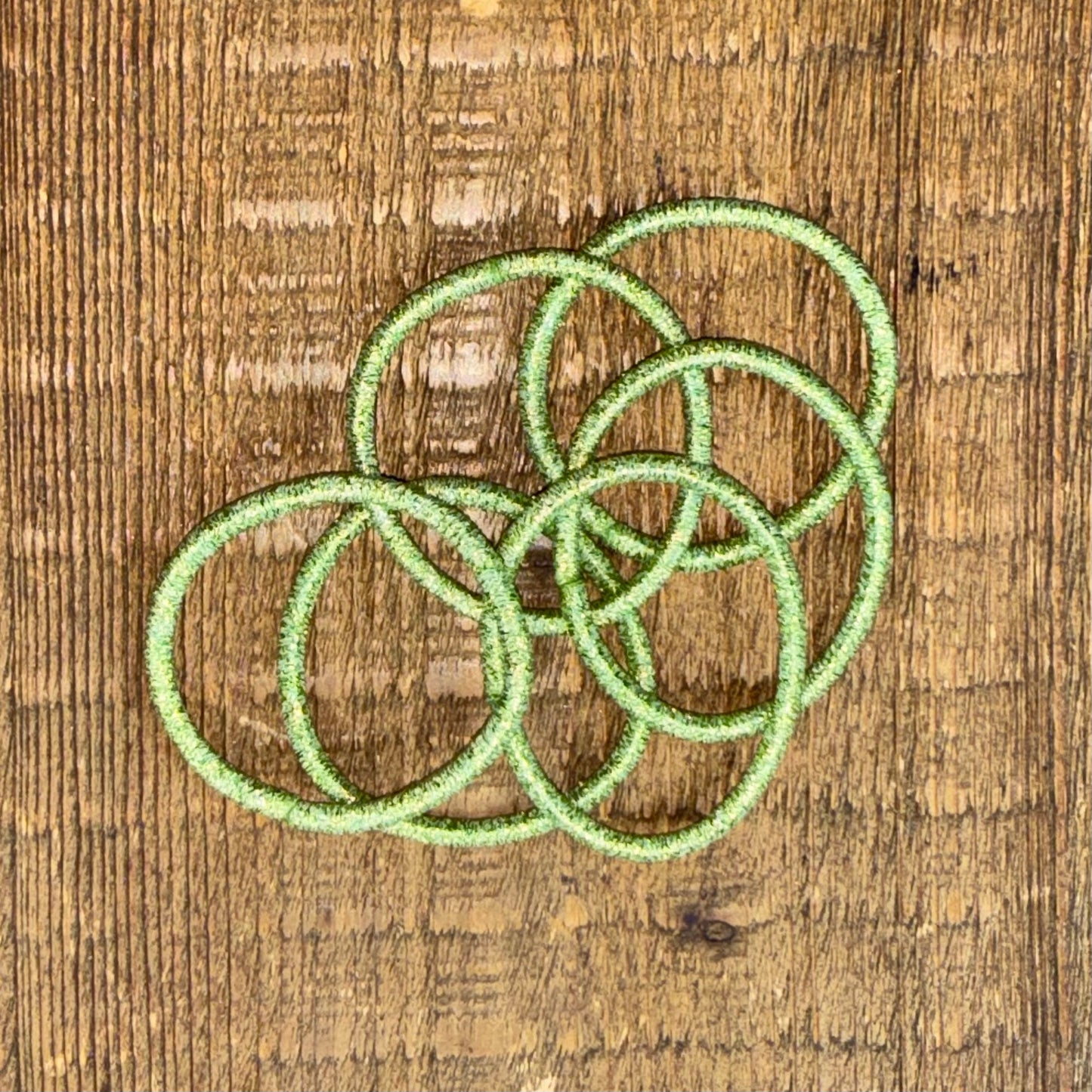 6 bright green metallic hair elastics for girls placed overlapping on wood background.