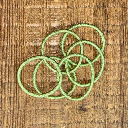 6 bright green metallic hair elastics for girls placed overlapping on wood background.