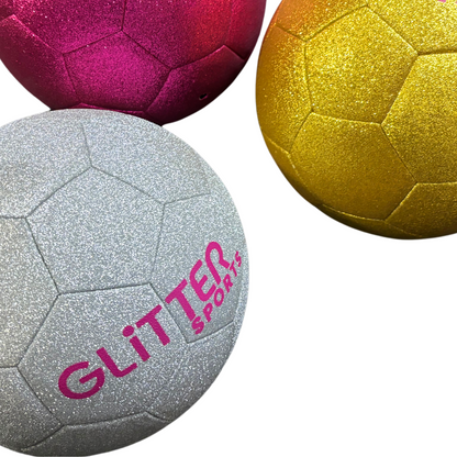 Silver glitter soccer ball with pink 'Glitter Sports' logo next to pink and gold soccer balls on white background.