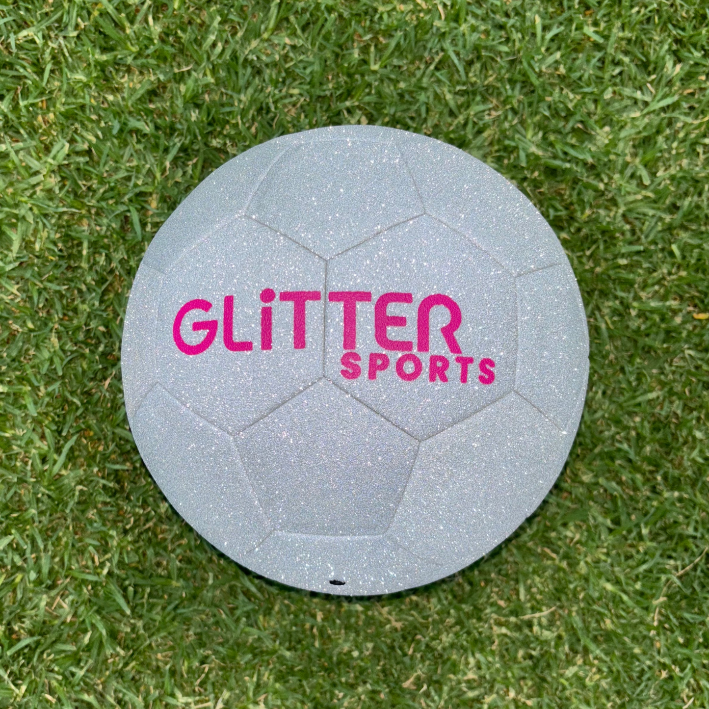 Sparkly, size 5 silver glitter soccer ball with pink 'Glitter Sports' logo on grass background.