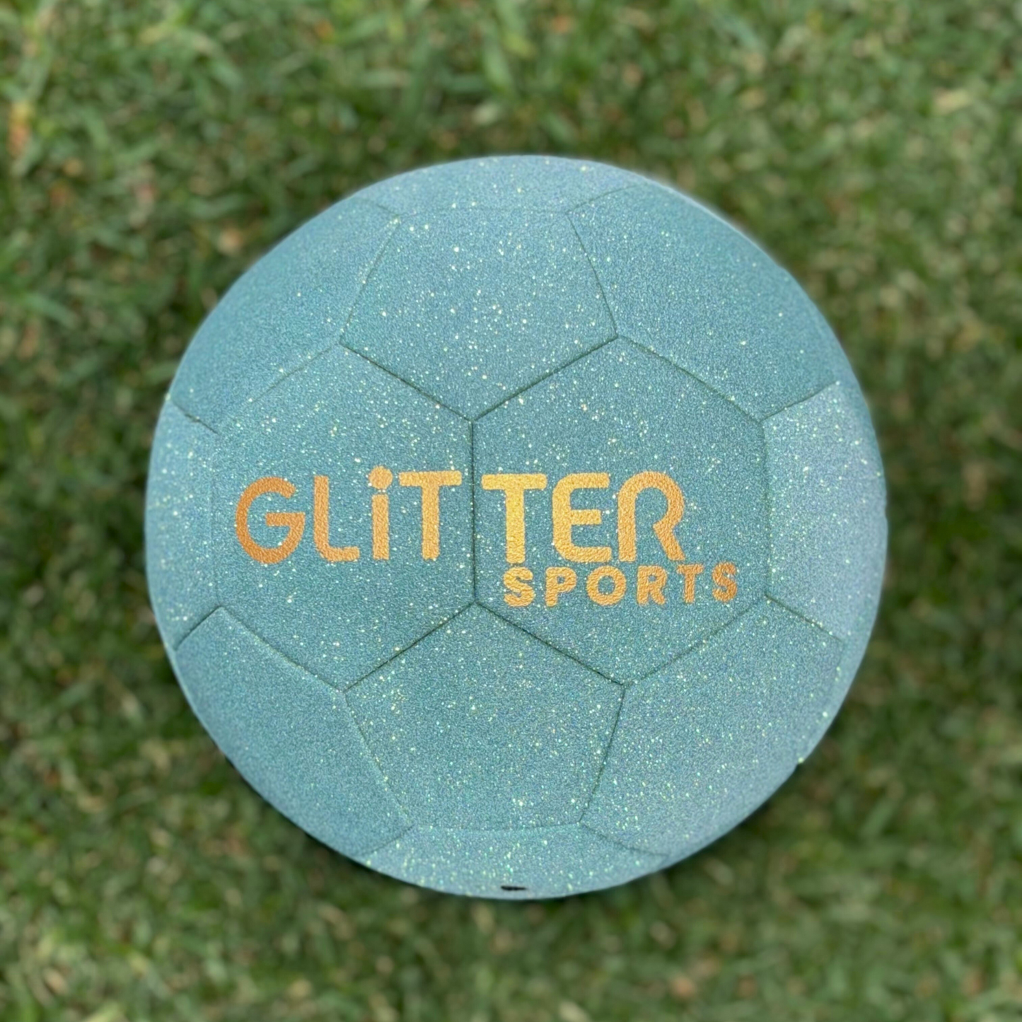 Size 5 sparkling mint green glitter soccer ball with gold 'Glitter Sports' logo sitting on green grass.