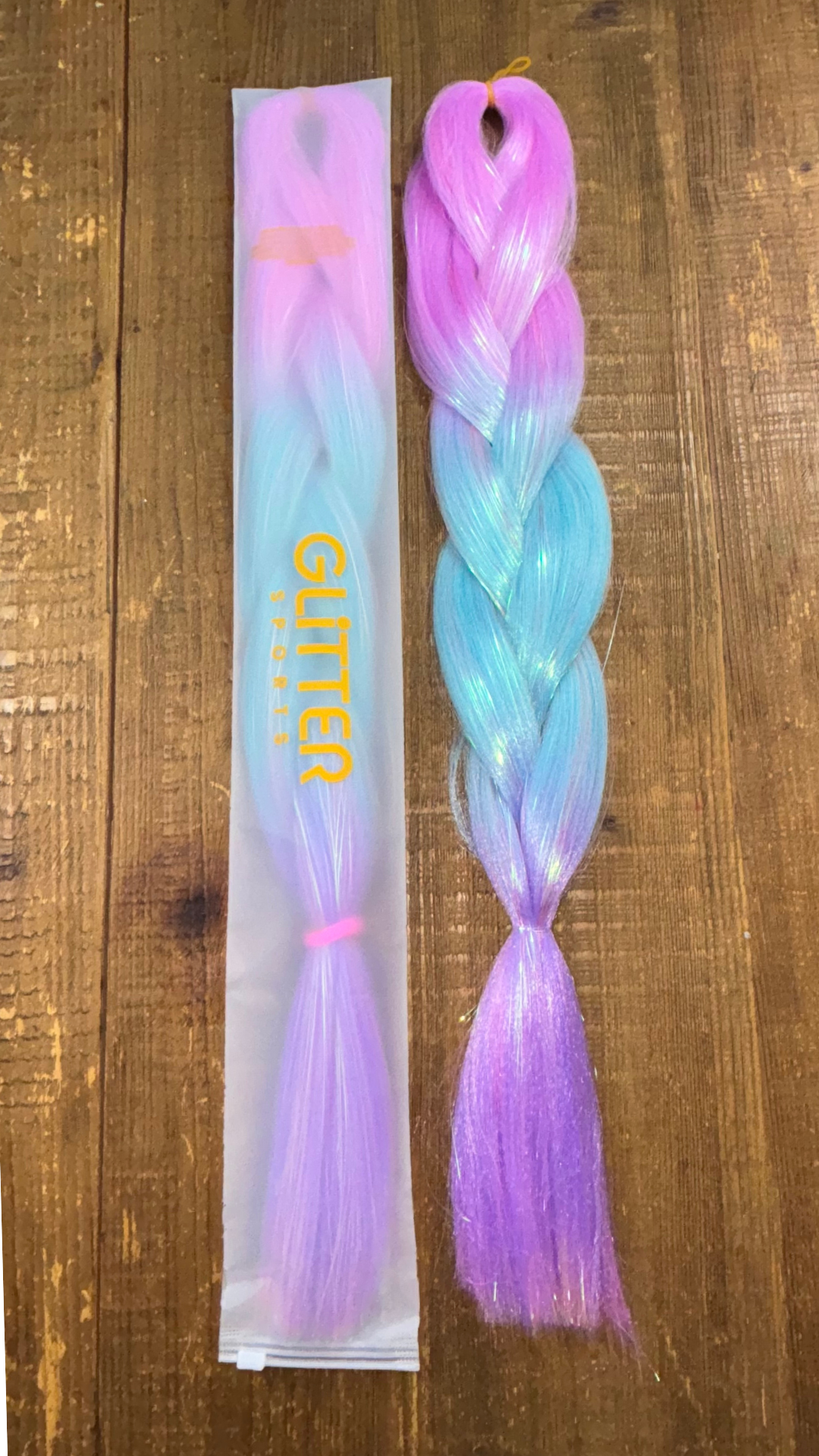 Pretty pink, bright blue and purple ombre tinsel hair extension braids laid on wood background.