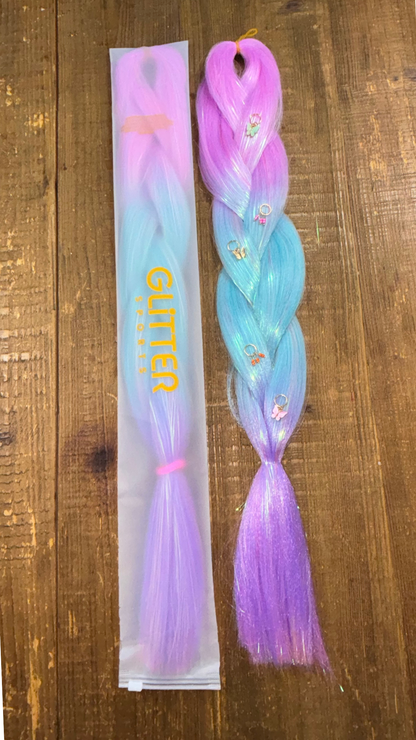 Two ombre synthetic hair extension braids with colours pink, blue and purple and golden butterfly hair charms on wood background.